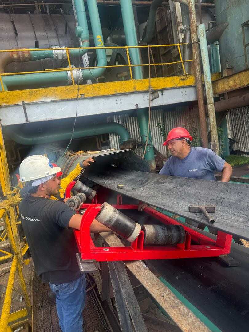 Technicians adjusting a red weigh frame on an industrial conveyor